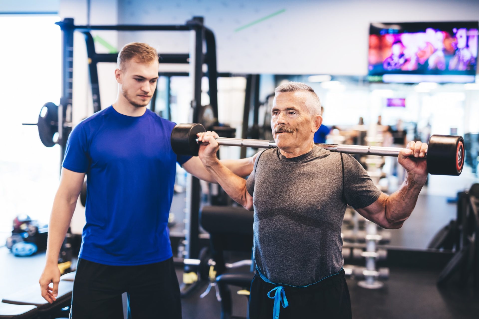 older-man-assisting-senior-man-at-the-gym-e1677564441929.jpg